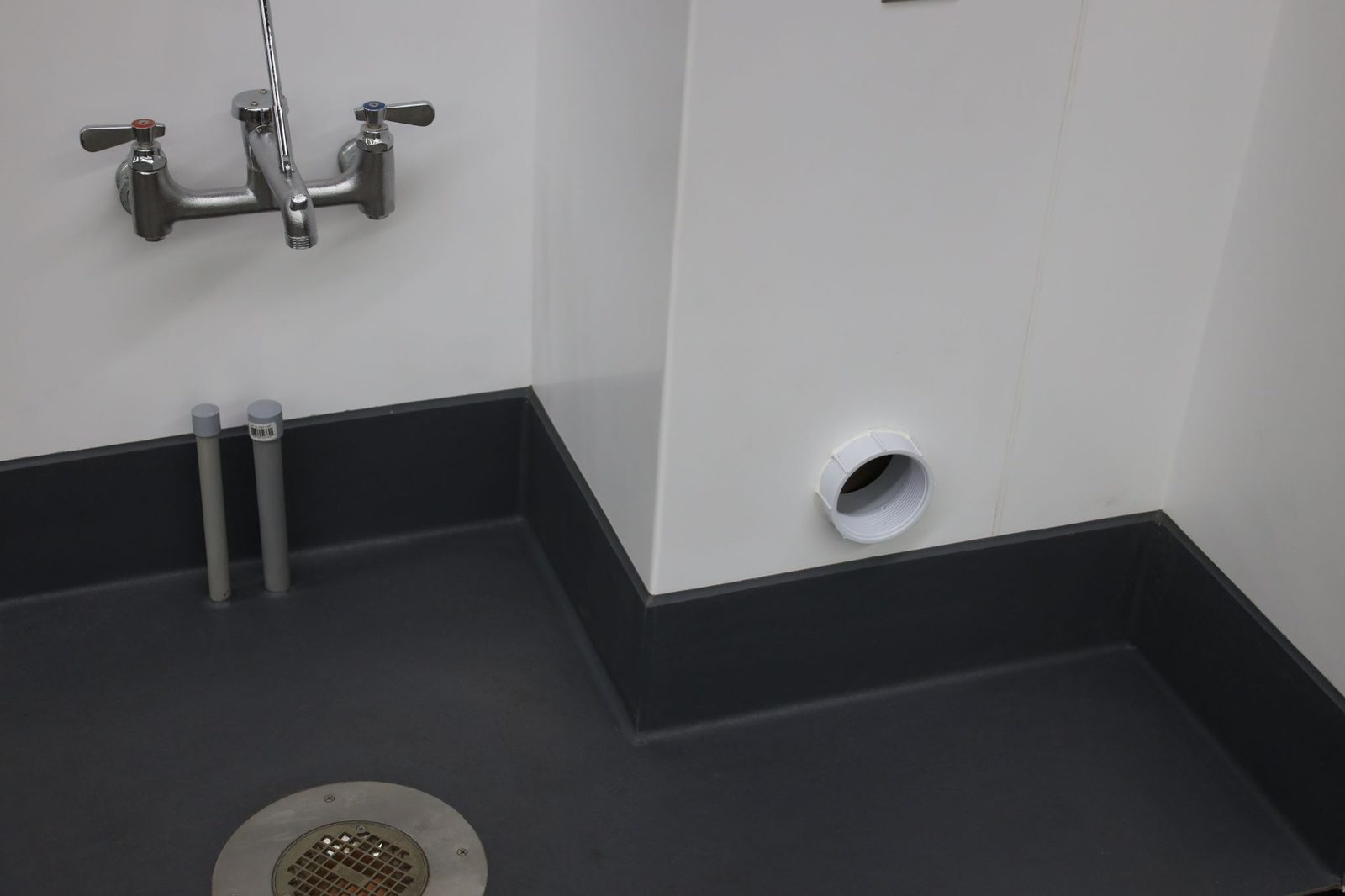 Eco-Grip detail work around a mop sink — floor drain, pipe penetrations, and cove terminations